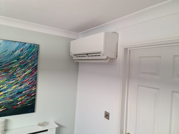 A white wall-mounted Panasonic air conditioning unit installed high on the wall of a home interior