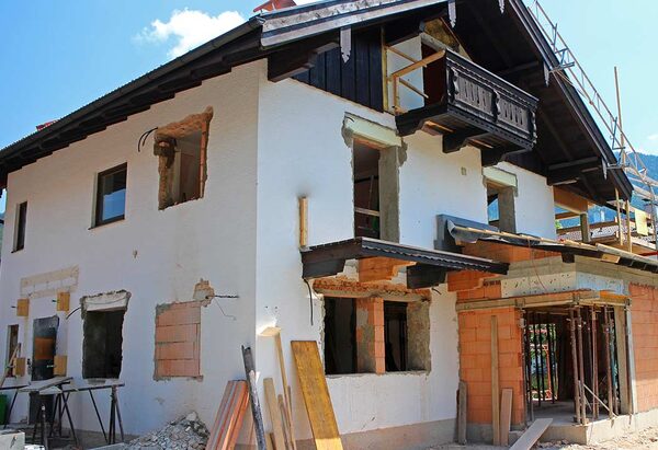 A large house under renovation with exposed brickwork, unfinished window openings and scaffolding