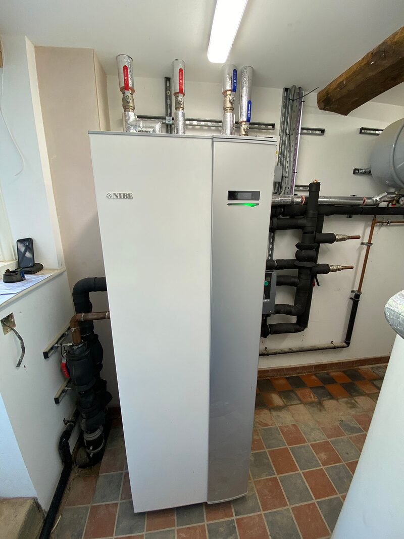 A NIBE ground source heat pump unit installed indoors with connected pipework and manifolds