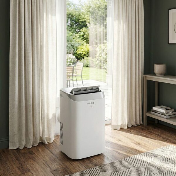 A white electriQ portable air conditioner standing in a living room beside open patio doors