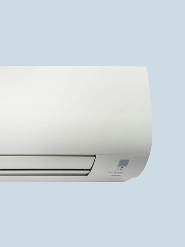 A white wall-mounted air conditioning indoor unit shown against a plain pale blue background