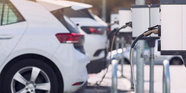 Electric cars parked at a row of public EV charging points with charging cables plugged in
