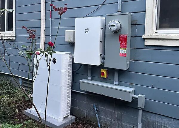 A Sigenergy home battery and inverter installed on the exterior wall of a house next to an electricity meter
