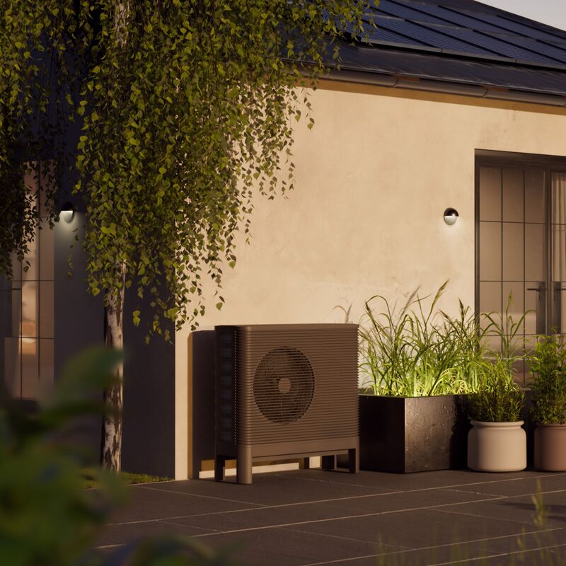 An Aira air source heat pump outdoor unit installed on a terrace beside a modern house with solar panels on the roof
