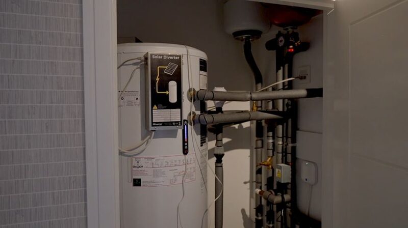 A Mixergy hot water cylinder with a Solar Diverter unit installed in an airing cupboard with pipework and valves