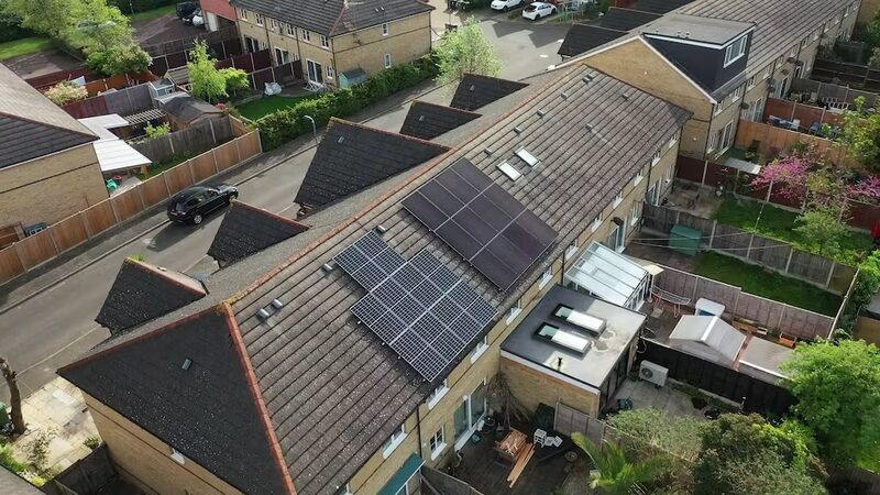Aerial view of solar panel arrays on the tiled roofs of UK terraced houses