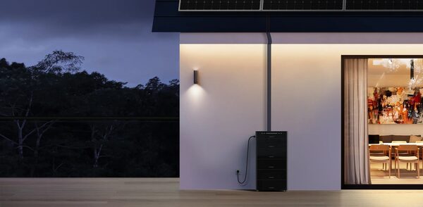 A Marstek home battery storage unit installed on an exterior house wall at dusk beneath rooftop solar panels