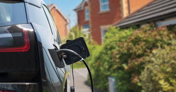 An electric car plugged in with a charging cable on a UK residential driveway