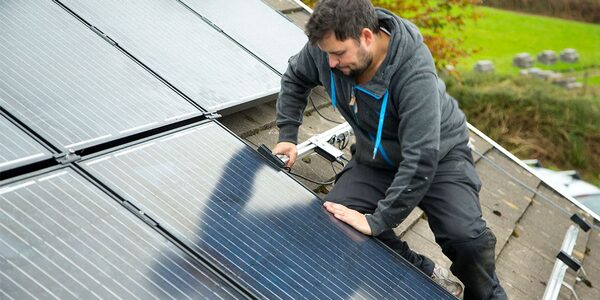 An installer fitting solar panels on a tiled roof