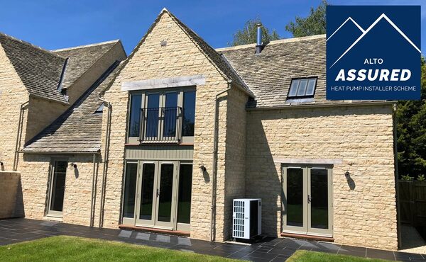 A stone house with an air source heat pump unit installed outside, overlaid with the Alto Assured Heat Pump Installer Scheme logo
