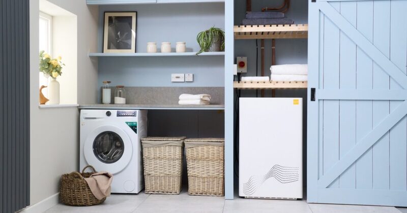 A white tepeo heat battery boiler installed in a utility room next to a washing machine and shelving
