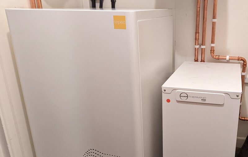 A tepeo low-carbon electric thermal battery boiler installed next to a Klasher Thermo cylinder with copper pipework in a home utility space