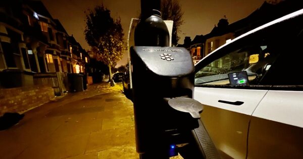 A char.gy EV charge point on a residential street at night with a car plugged in