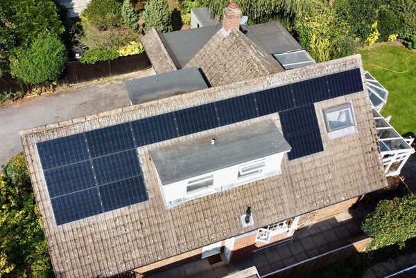 Aerial view of a UK house roof with black solar panels installed around a dormer window