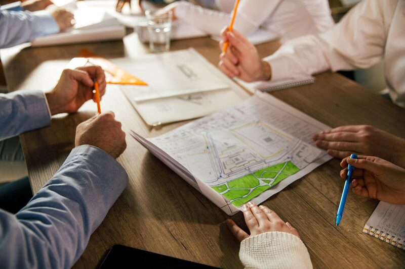People around a table reviewing printed plans and drawings with pens