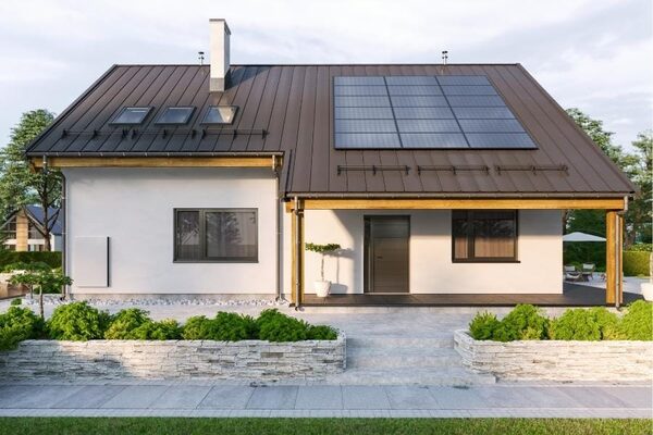 A modern single-storey house with solar panels on its dark metal roof
