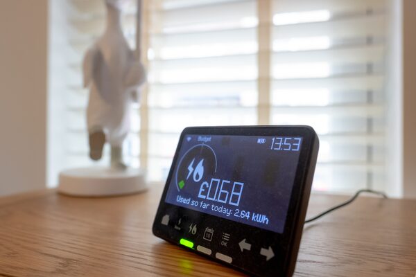 A smart energy monitor in-home display on a wooden table showing today's energy cost of £0.68 and 2.64 kWh used