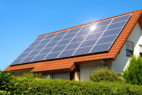 Solar panels covering the tiled roof of a house on a sunny day