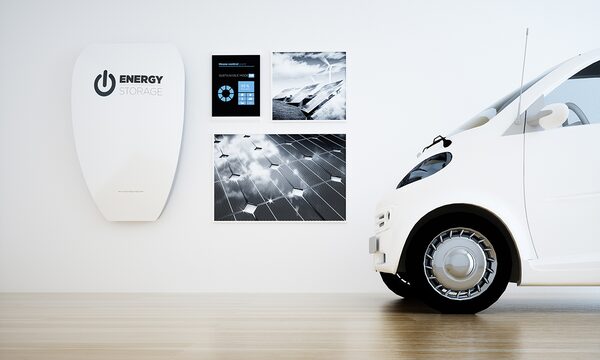 A white home battery unit labelled 'Energy Storage' mounted on a wall next to a small white electric car