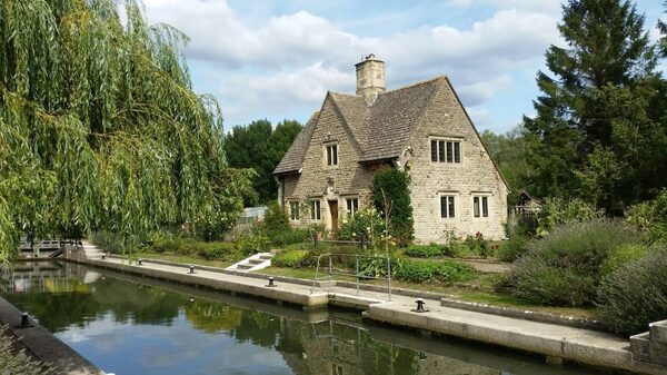 A stone cottage beside a canal or river, illustrating a waterside home suitable for a water source heat pump