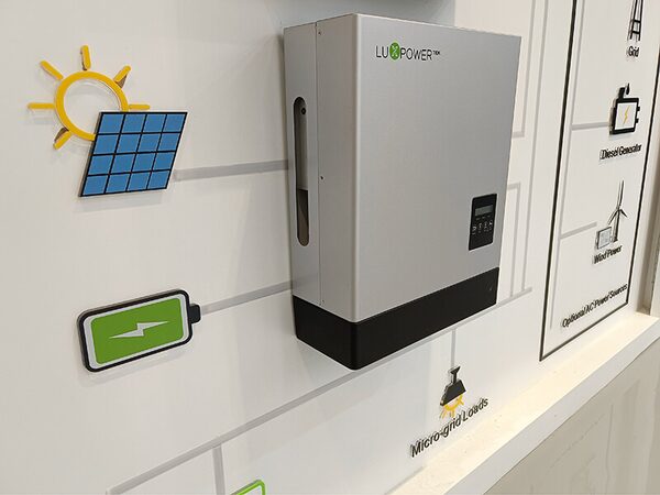 A LuxPowerTek hybrid solar inverter mounted on a display wall with cut-out icons showing a solar system diagram