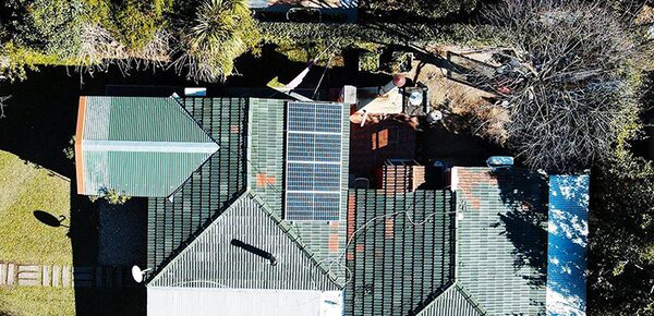 Aerial view of a house roof with a small array of solar panels installed on tiled roofing