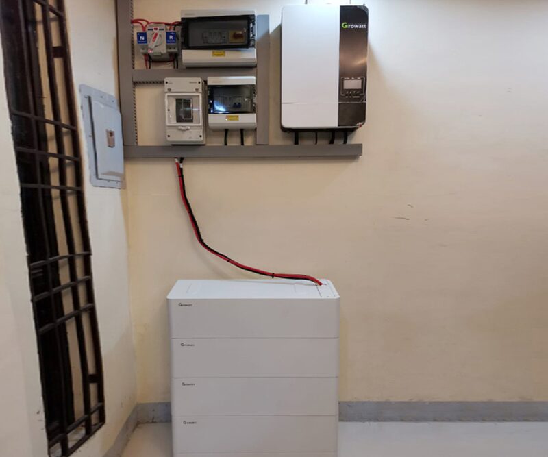 A Growatt wall-mounted off-grid inverter with consumer units and a stacked battery unit installed on a wall