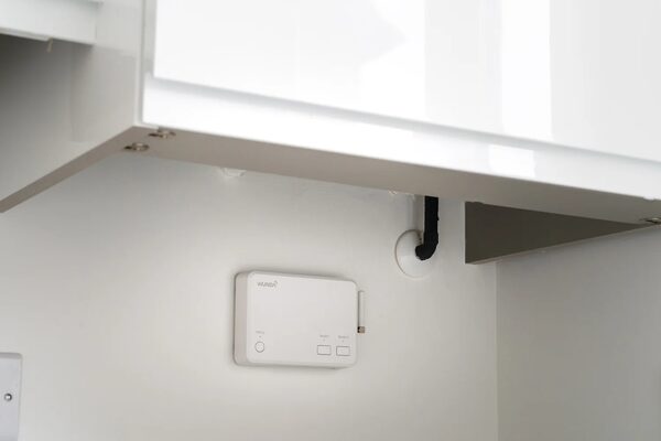 A white WundaSmart hub control unit mounted on a wall under a kitchen cabinet