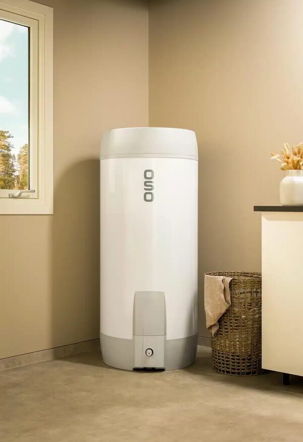 A white OSO hot water cylinder installed in the corner of a home utility room next to a window and laundry basket