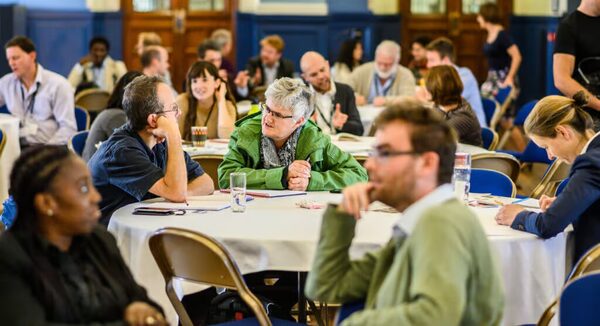 People talking at round tables in a community workshop event