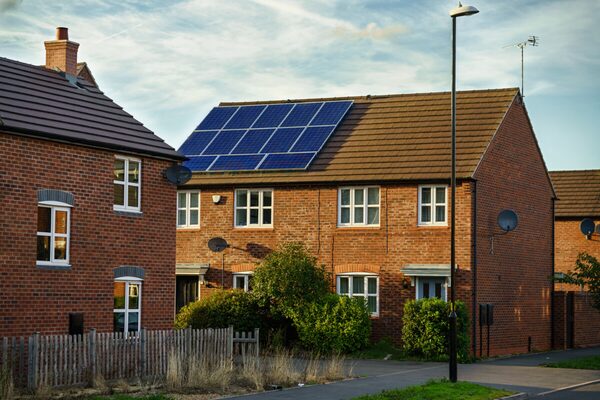 Solar PV panels installed on the tiled roof of a brick semi-detached house on a residential street