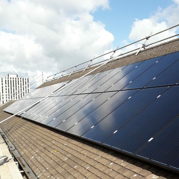 A large array of solar panels fitted on a tiled roof with scaffolding poles alongside