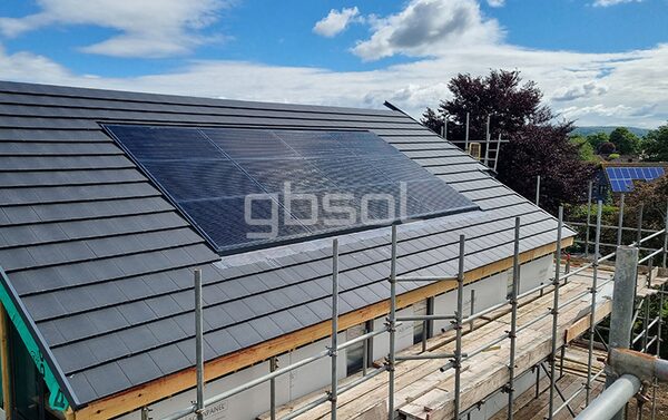 An in-roof solar panel array installed on a slate-roofed house surrounded by scaffolding during construction