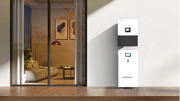 A LuxpowerTek hybrid inverter and matching battery unit mounted on a white wall next to a glass door into a living room