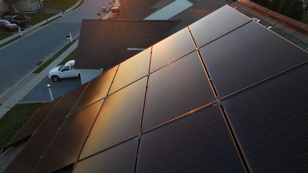 Rooftop solar panels on a suburban house at sunset, seen from above