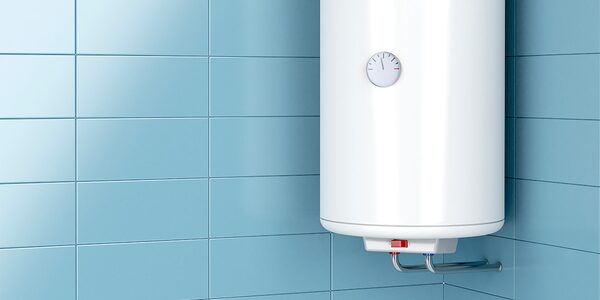 A white wall-mounted hot water cylinder with a dial thermostat, installed on blue tiled bathroom wall