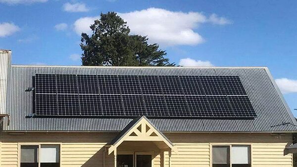 A house with a large array of solar panels installed on its corrugated metal roof