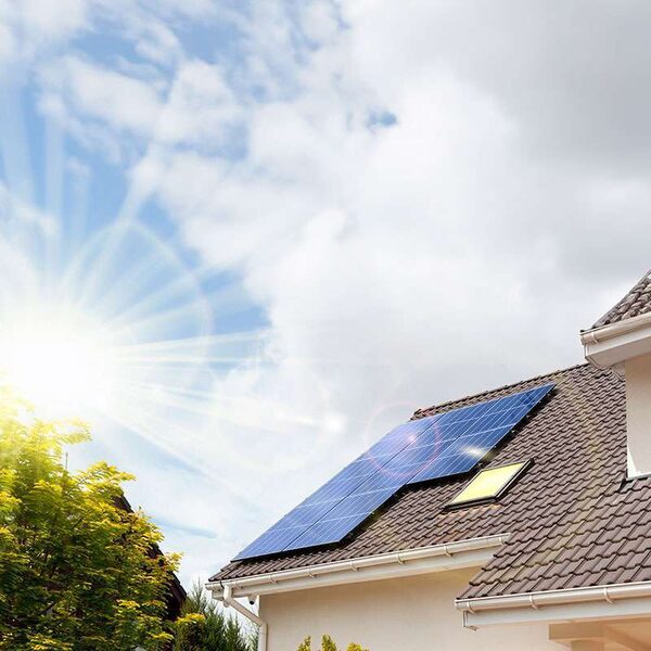 Solar panels installed on the tiled roof of a house under a bright sunny sky