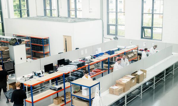 Workers assembling EV chargers on benches in Andersen EV's production facility