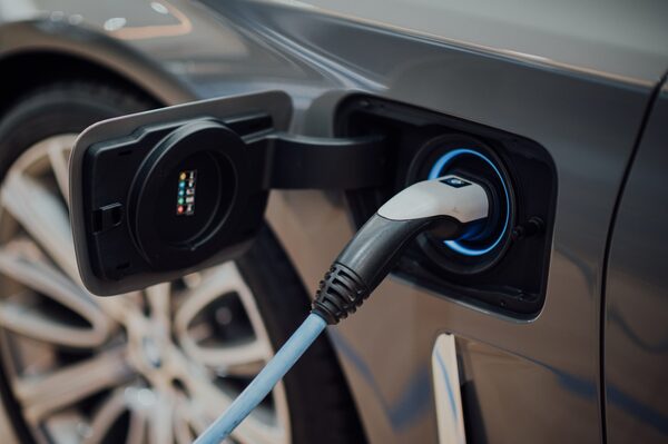 A charging cable plugged into the charging port of a grey electric car