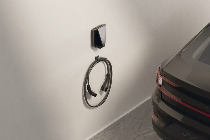 A wall-mounted Easee electric car charge point with coiled black charging cable next to a dark car in a garage