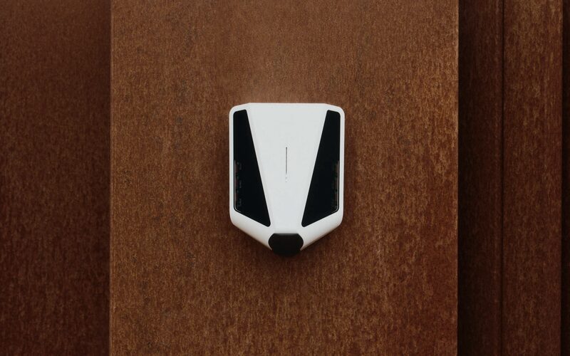 A white Easee home EV wall charger mounted on a rust-coloured wall