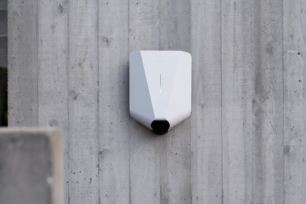 A white Easee wall-mounted EV charger installed on a grey concrete wall