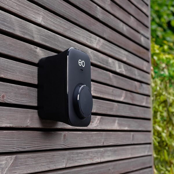 A black EO electric car charging point mounted on a wooden slatted exterior wall