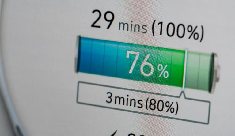 Close-up of an electric car dashboard display showing a battery at 76% charge with estimated charging times of 29 minutes to 100% and 3 minutes to 80%