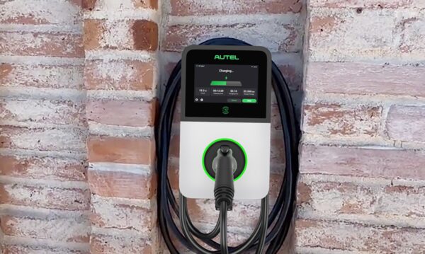 An Autel MaxiCharger AC Pro wall-mounted EV charge point with a charging cable plugged in, mounted on a brick wall