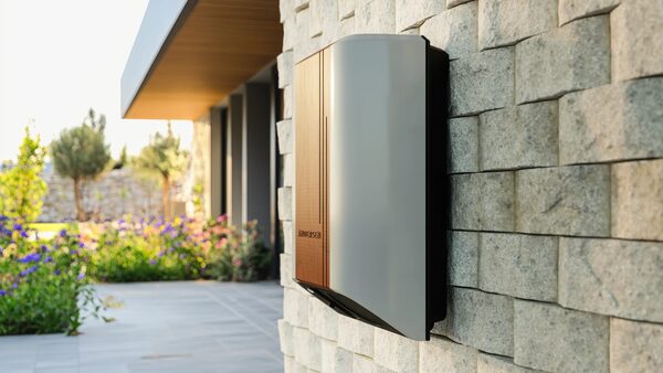 An Andersen EV home charge point mounted on a stone wall outside a modern house