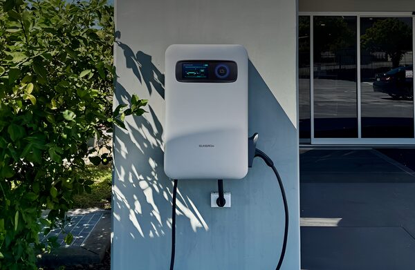 A white Sungrow wall-mounted EV charger with a display screen and tethered cable installed on an exterior wall