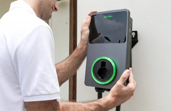 A man mounting an Autel wall-mounted EV charge point on an exterior wall