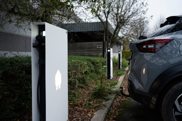 Electric vehicle charge points installed outdoors beside a parked grey car